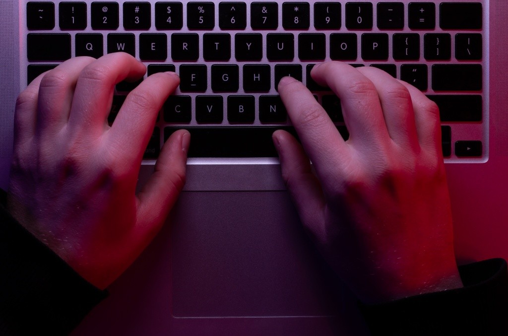 man-uses-laptop-closeup-male-hands-neon-lighting-top-view.jpg