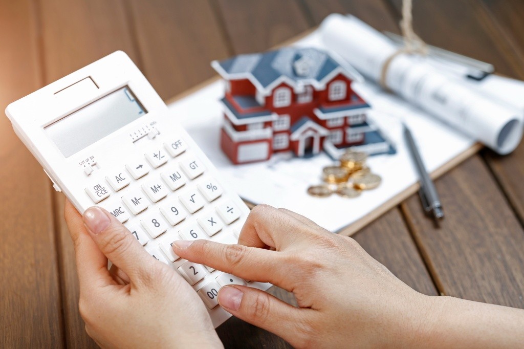 a-female-hand-operating-a-calculator-in-front-of-a-villa-house-model.jpg