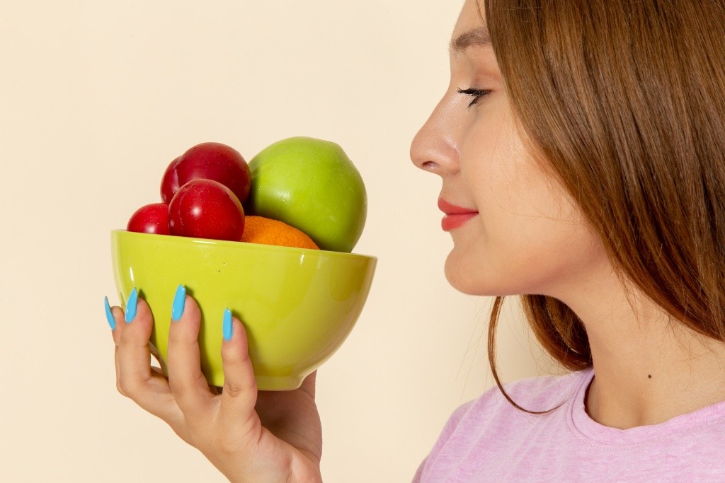 front-view-young-female-pink-t-shirt-blue-jeans-holding-plate-with-fruits-smelling-it.jpg